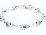 a close up of a bracelet with green stones and diamonds