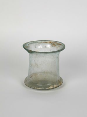 a small glass vase with a rusted rim on a white surface