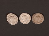 three ancient roman coins on a black background