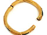 an image of a gold and green bracelet on a white surface