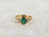 gros plan d'une bague en or avec une pierre verte