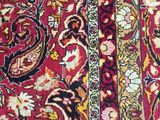 a close up of a red and black oriental rug on a wooden floor
