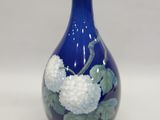 un vase bleu orné de fleurs blanches sur fond blanc