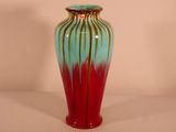 un vase rouge et bleu posé sur une table blanche