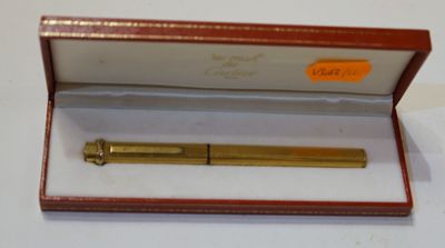 un stylo doré dans un coffret rouge posé sur une surface blanche