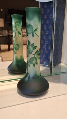 two green vases sitting on a shelf next to a mirror