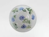 a glass bowl with blue flowers on it on a white surface