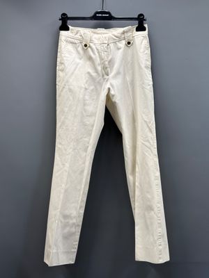 un pantalon blanc suspendu à un cintre devant un mur gris