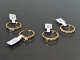 three gold rings with tags on them sitting on top of a table