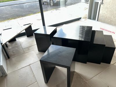 three tables and two stools in the corner of a room