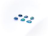 a group of blue and green oplite stones on a white surface