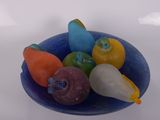 un saladier bleu rempli de fruits et de légumes posé sur une table blanche