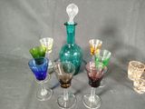 five different colored glass wine glasses and a bottle on a table