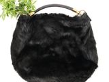 the black fur purse is holding a plant on top of it