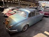 an old car is parked in a garage with other cars in the background