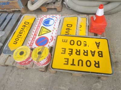 de nombreux panneaux différents posés sur une palette à côté d'une borne d'incendie