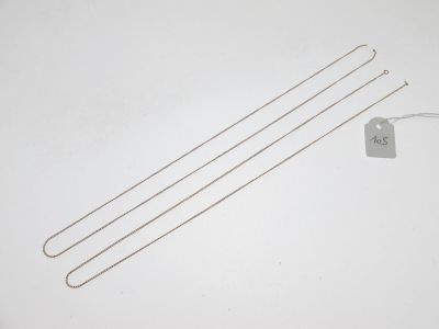 trois aiguilles à tricoter plaquées argent et une étiquette sur un fond blanc