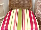 a wicker chair with a colorful striped seat pad