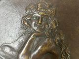 a bronze plaque of a woman sitting on a table