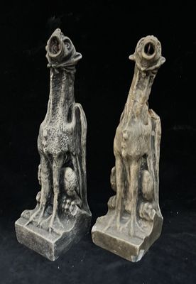 two statues of animals that are sitting on a black surface