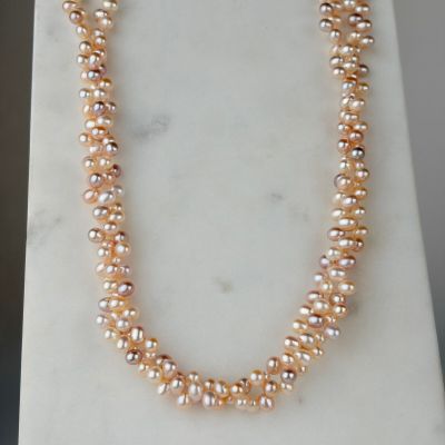 a close up of a necklace with pearls on a marble surface