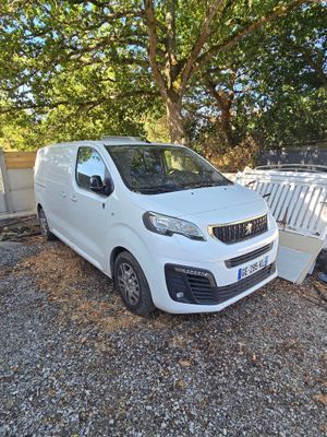une camionnette blanche garée à côté d'un tas d'ordures sur un terrain en gravier