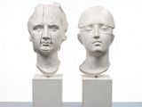 two white sculptures of heads are sitting on top of each other