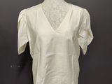a white top on a mannequin stand against a black wall