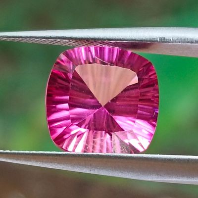purple gems are being held by a pair of pliers on a wire