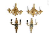 three wall sconces with a clock on each of them on a white surface