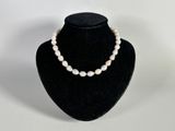 a close up of a necklace with pearls on a mannequin