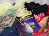 a pile of children ' s clothing and books on a bed
