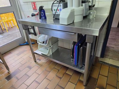 une cuisine équipée d'une table en inox sur laquelle se trouve un micro-ondes