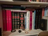 a shelf with many books and a cup on it