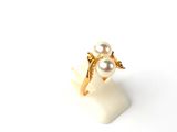 bague en or ornée de perles et de feuilles sur un fond blanc
