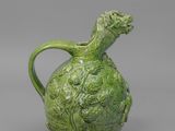 un vase vert surmonté d'une tête de dragon