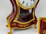 a red and gold clock sitting next to a small box