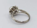 a close up of a ring with a pearl and diamonds on it