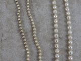 trois colliers de perles posés sur une table, à côté d'une paire de ciseaux