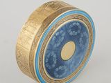 gold and blue clock sitting on top of a white surface