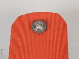 an orange sweater with a silver button on top of it