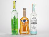 trois bouteilles d'alcool sont alignées sur une surface blanche