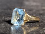 une bague sertie d'une topaze bleue, posée sur une table