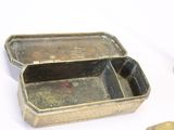 a small metal box with a lid on a white surface