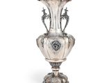 un vase ancien en argent posé sur un socle en métal