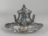 an antique silver plate with a teapot on it on a white surface