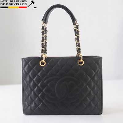 un sac Chanel noir muni d'une poignée en chaîne dorée