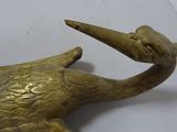brass statue of a bird with a long beak on a white surface