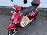 un scooter rouge garé devant un mur blanc