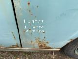 a rusted blue car with numbers on the side of it